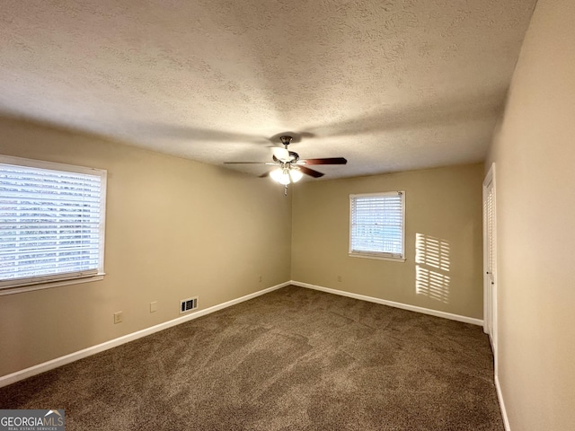 spare room with ceiling fan, a textured ceiling, and dark colored carpet