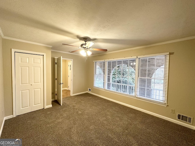 unfurnished bedroom featuring ceiling fan, dark carpet, crown molding, and a textured ceiling