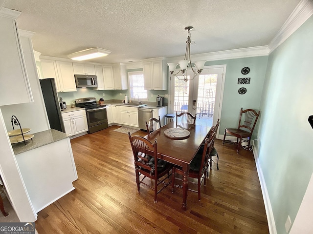 dining area with sink, dark wood-type flooring, ornamental molding, french doors, and a chandelier