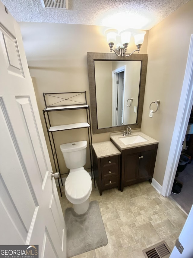 bathroom with a textured ceiling, toilet, vanity, and a chandelier