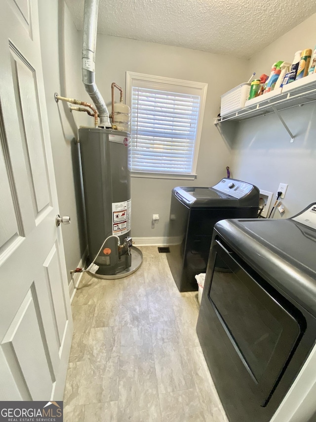 washroom featuring a textured ceiling, independent washer and dryer, and gas water heater