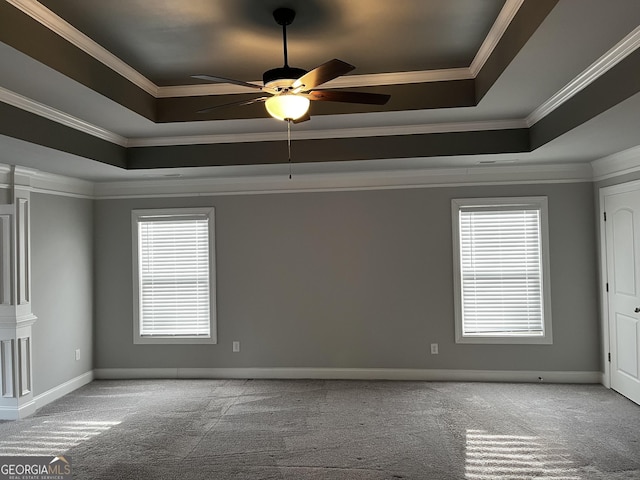 carpeted empty room featuring ornamental molding, ceiling fan, and a tray ceiling