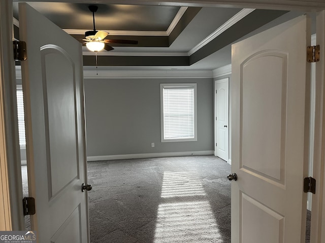 carpeted empty room featuring crown molding, ceiling fan, and a tray ceiling