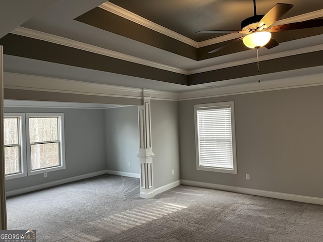 carpeted empty room featuring a raised ceiling, crown molding, and plenty of natural light