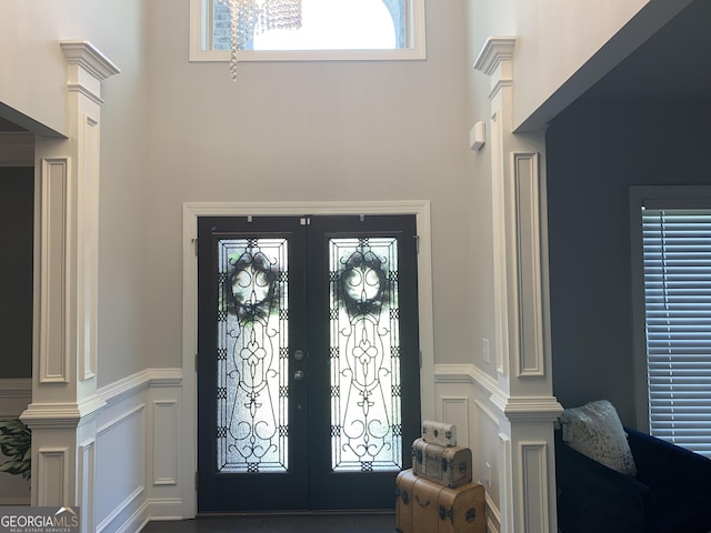 foyer entrance with ornate columns, a towering ceiling, and french doors