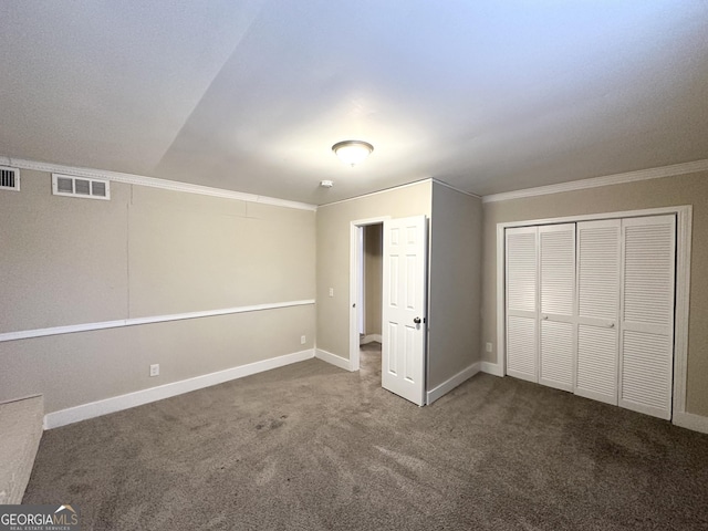 unfurnished bedroom with a closet, ornamental molding, and dark colored carpet