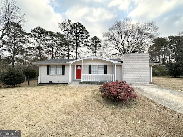 ranch-style home featuring covered porch and a front lawn