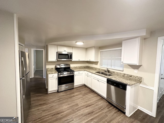 kitchen with light stone countertops, appliances with stainless steel finishes, white cabinetry, and sink