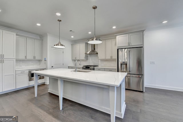 kitchen with sink, hanging light fixtures, stainless steel appliances, light stone counters, and an island with sink