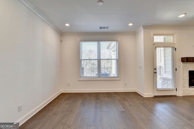 entryway featuring a stone fireplace, a wealth of natural light, and ornamental molding