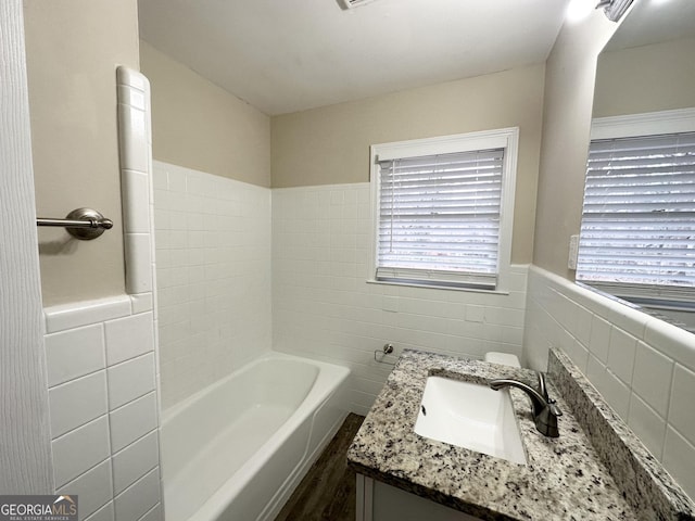 bathroom featuring vanity, a bathtub, and tile walls