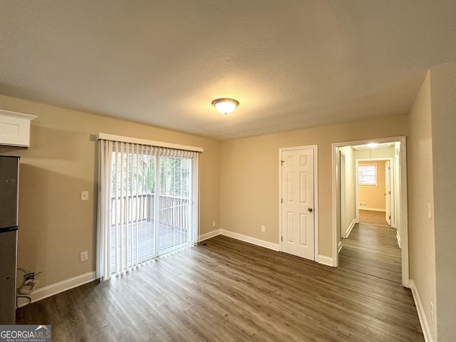 spare room featuring a textured ceiling and dark wood-type flooring