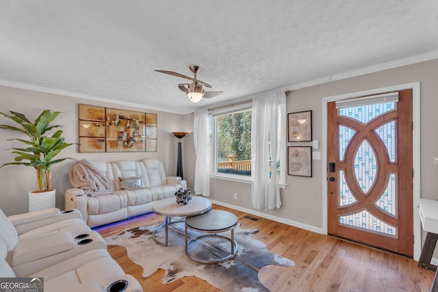 living room featuring ornamental molding, a textured ceiling, ceiling fan, and light hardwood / wood-style flooring