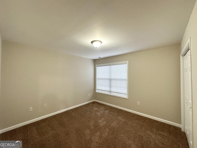 unfurnished room featuring dark carpet