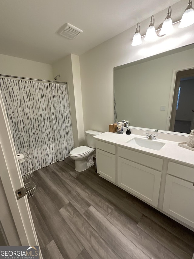 bathroom featuring a shower with shower curtain, vanity, toilet, and wood-type flooring