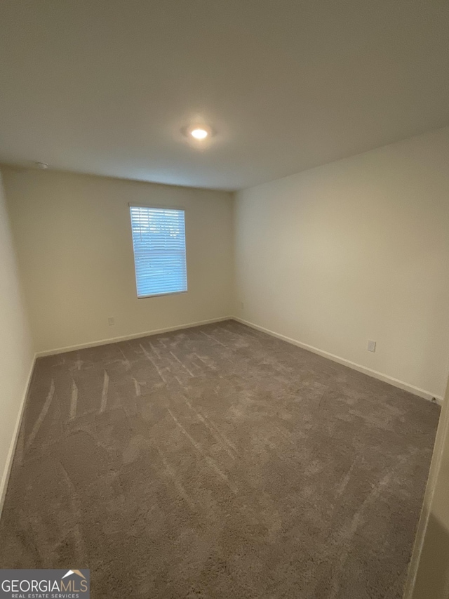 unfurnished room featuring dark carpet