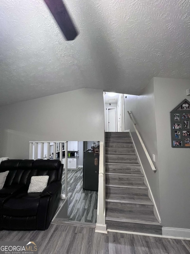 staircase featuring hardwood / wood-style flooring, lofted ceiling, and a textured ceiling