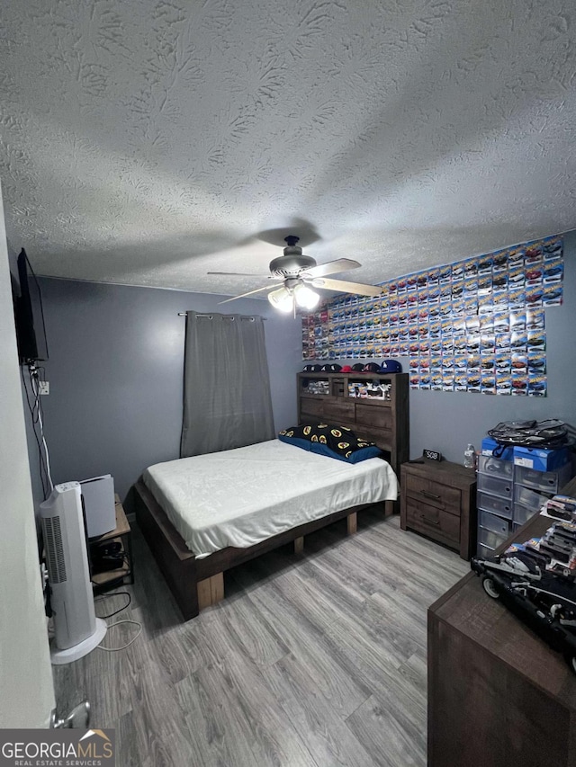 bedroom featuring ceiling fan, a textured ceiling, and hardwood / wood-style flooring