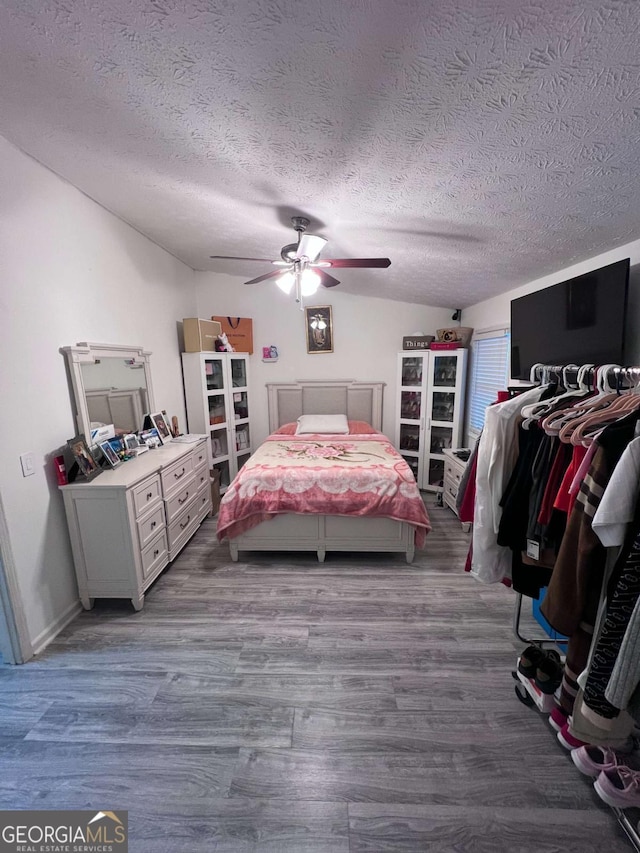 bedroom featuring hardwood / wood-style floors, a textured ceiling, and ceiling fan