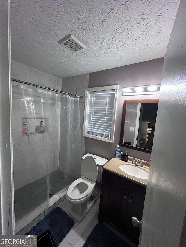 bathroom with tile patterned floors, vanity, a textured ceiling, toilet, and curtained shower