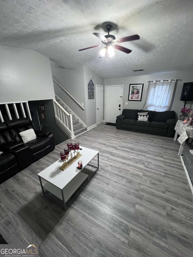 living room featuring wood-type flooring, a textured ceiling, and ceiling fan