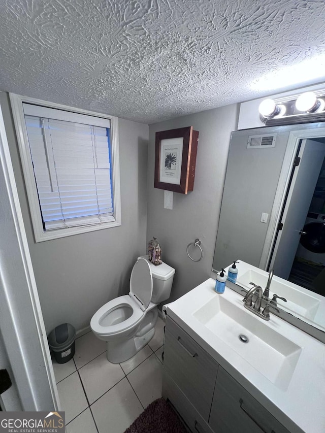 bathroom featuring tile patterned flooring, vanity, a textured ceiling, and toilet