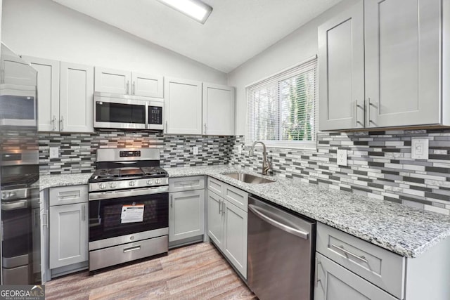 kitchen with decorative backsplash, sink, lofted ceiling, and appliances with stainless steel finishes