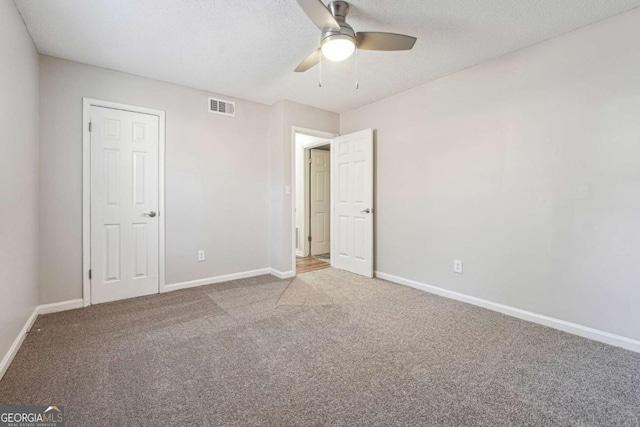 unfurnished bedroom featuring ceiling fan, carpet floors, and a textured ceiling