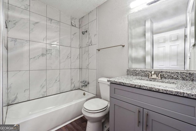 full bathroom with vanity, hardwood / wood-style flooring, tiled shower / bath combo, toilet, and a textured ceiling