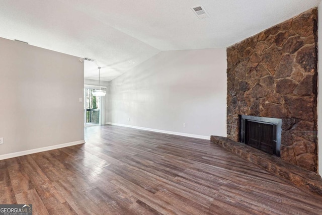 unfurnished living room featuring dark hardwood / wood-style floors, a stone fireplace, and lofted ceiling