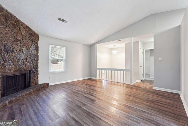 unfurnished living room with a textured ceiling, a fireplace, dark wood-type flooring, and vaulted ceiling