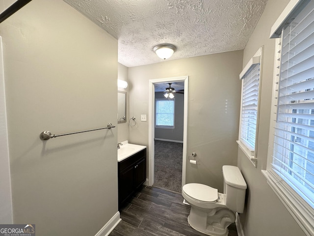 bathroom with vanity, ceiling fan, toilet, and a textured ceiling