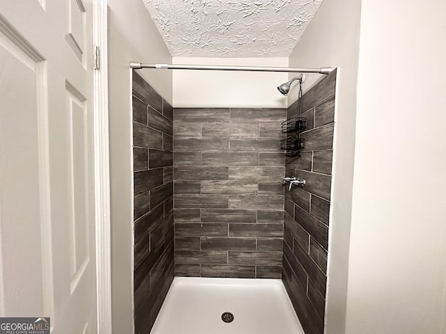 bathroom featuring a tile shower and a textured ceiling