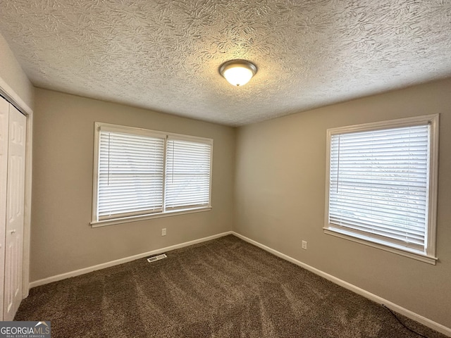 carpeted empty room featuring a textured ceiling