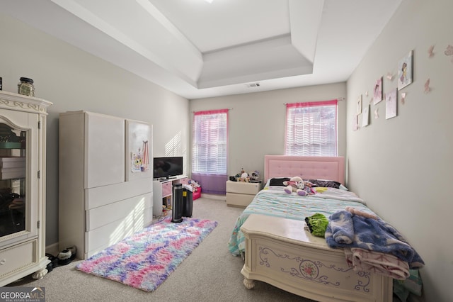 bedroom with light colored carpet and a tray ceiling