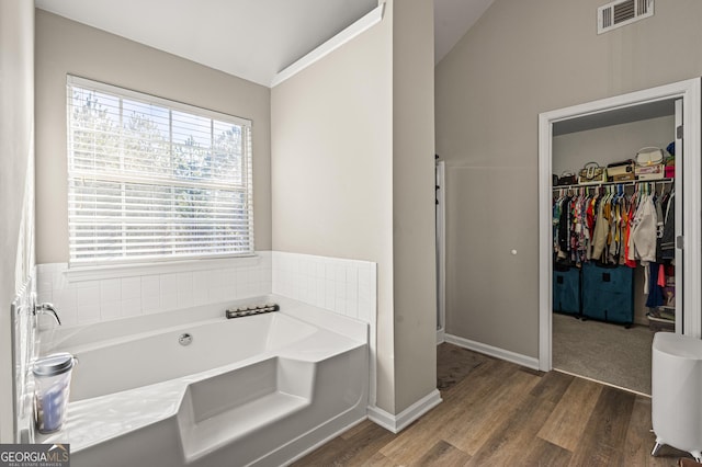 bathroom featuring vaulted ceiling, a bathing tub, and hardwood / wood-style flooring