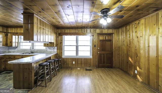 kitchen with sink, wooden ceiling, a kitchen breakfast bar, kitchen peninsula, and light wood-type flooring