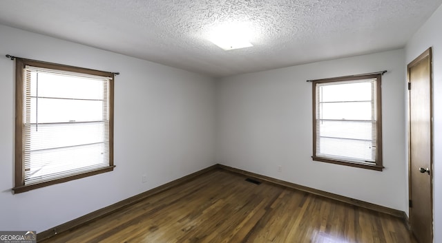 spare room featuring dark hardwood / wood-style floors and a textured ceiling