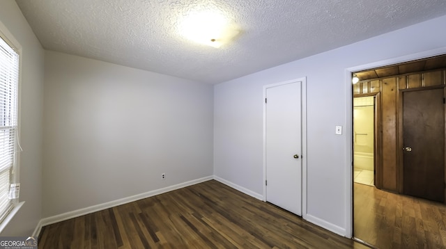 unfurnished bedroom featuring a textured ceiling and dark hardwood / wood-style floors