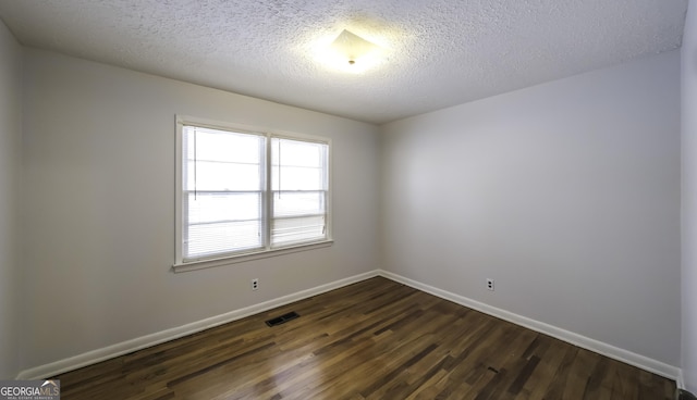 empty room with dark wood-type flooring and a textured ceiling