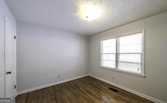 spare room with dark hardwood / wood-style flooring and a textured ceiling