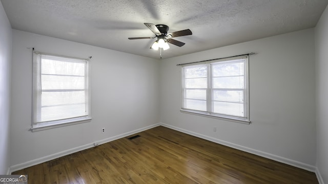 spare room featuring a textured ceiling, dark hardwood / wood-style floors, plenty of natural light, and ceiling fan