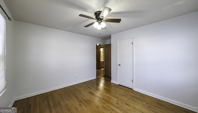 spare room with a textured ceiling, dark hardwood / wood-style floors, plenty of natural light, and ceiling fan