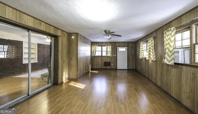 empty room featuring built in shelves, ceiling fan, dark wood-type flooring, and a textured ceiling