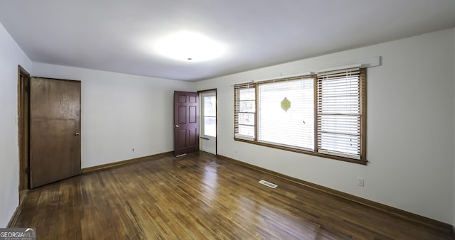 empty room with dark hardwood / wood-style flooring