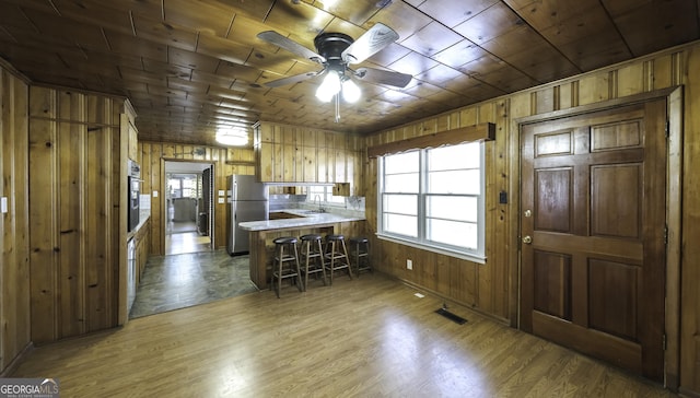 kitchen featuring a kitchen bar, kitchen peninsula, hardwood / wood-style flooring, and appliances with stainless steel finishes