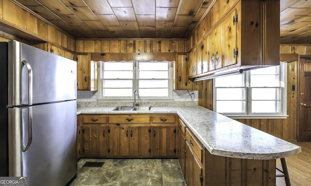 kitchen featuring sink, wooden ceiling, backsplash, kitchen peninsula, and stainless steel fridge