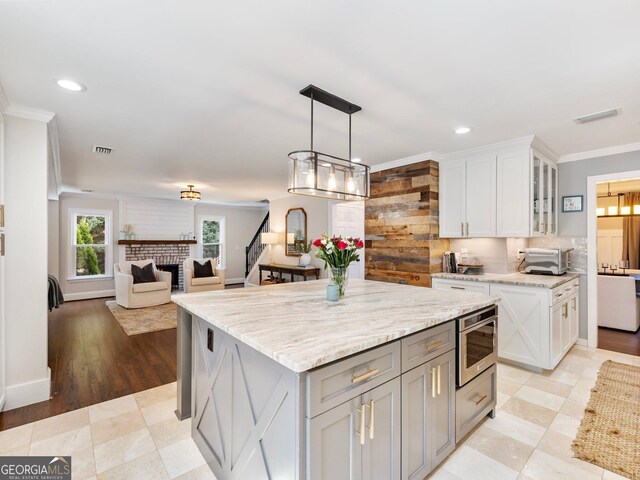 living area featuring an accent wall, ornamental molding, baseboards, and dark wood-style floors