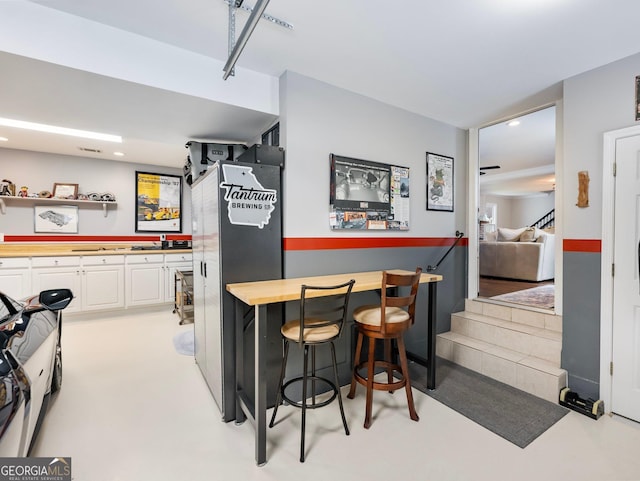 kitchen with a kitchen bar, wood counters, white cabinetry, and open shelves