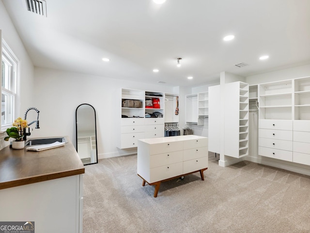 walk in closet with sink and light carpet